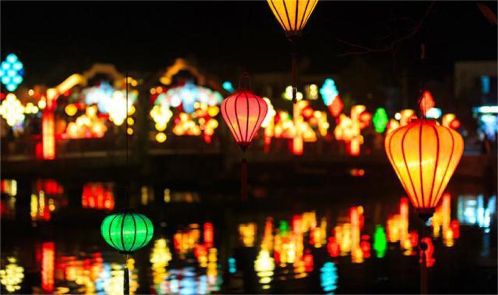 Colorful lanterns, combined with the lights reflecting from the ancient riverside houses, create a magical and captivating scene