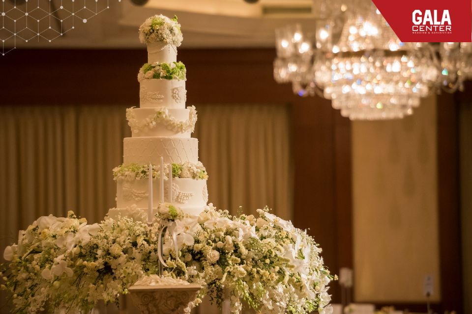 Thiết kế b&aacute;nh cưới nhiều tầng kết hợp h&agrave;i h&ograve;a với &aacute;nh s&aacute;ng s&acirc;n khấu gi&uacute;p kh&ocirc;ng gian tiệc cưới trở n&ecirc;n sang trọng v&agrave; c&acirc;n đối